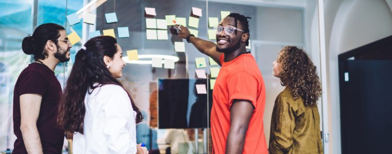 A group of people collaborating on a wall with post-it notes