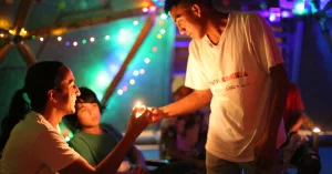 Two people lighting candles at a gathering for SOLE Colombia