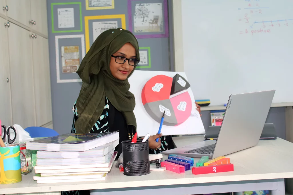 A teacher is teaching in a virtual way in a school classroom to prevent the spread of the corona virus.