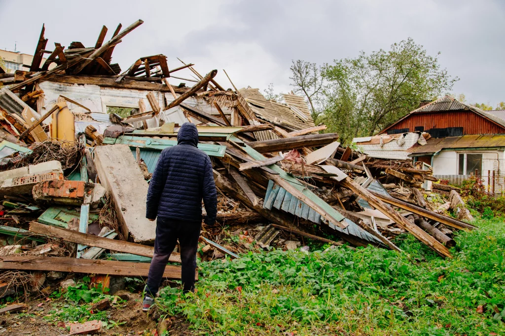 Sad man on ruined house. Hopeless, homelessness, result of natural disasters.