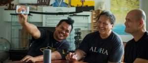 Three indigenous members smiling while looking at a cellphone