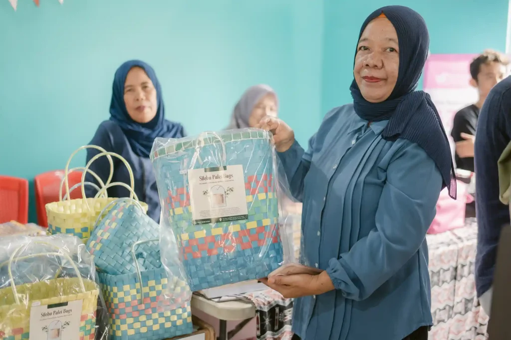 A woman from Indonesia displays a handbag she made herself.