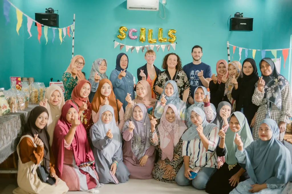 A group of beneficiaries of the SCILLS Program pose for the camera making the gesture of a heart.